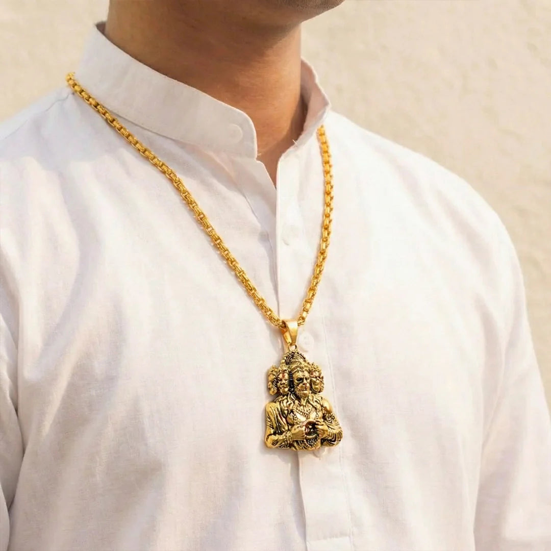 Gold necklace with a pendant on a white shirt against a beige background